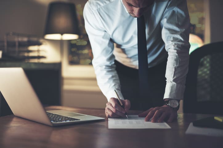 Serious businessman signing contract at office, working at night overtime